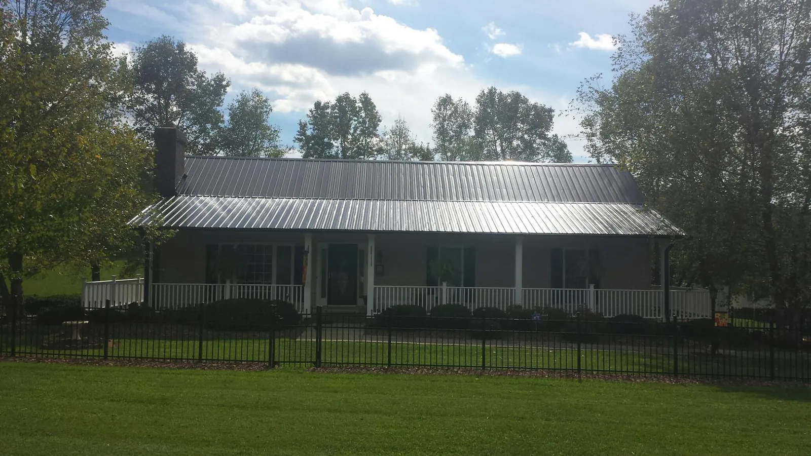 Gray metal roof on a brick ranch with a full width front porch — Gutter Guard Installation work by our crew in Hickman